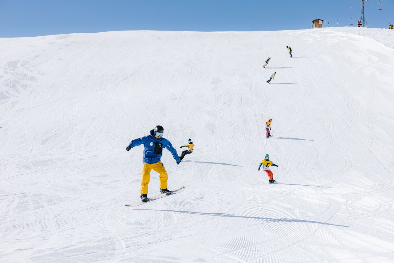 Snowboardgruppe der Skischule Arosa mit Snowboardlehrer auf der Piste
