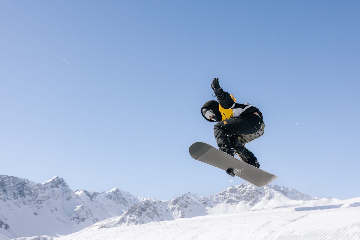 Snowboarderin springt über einen Kicker im Snowpark Tschuggen in Arosa
