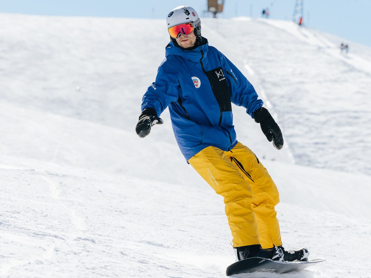 Snowboardlehrer der Skischule Arosa fährt im Privatunterricht in ruhiger Fahrt die Piste hinunter