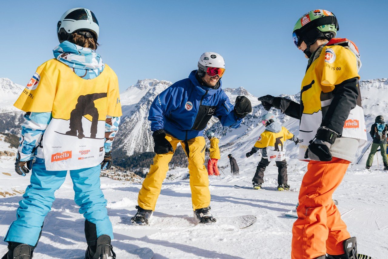 Snowboardlehrer der Skischule Arosa erklärt Kindern die nächste Übung