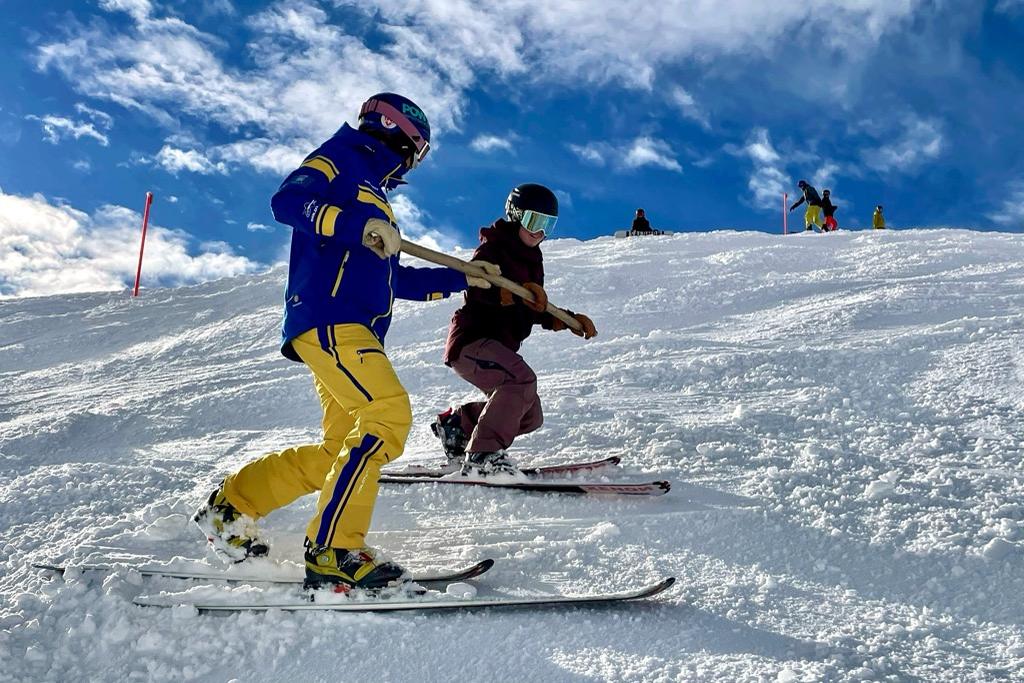 Schneesportlehrperson der Skischule Arosa zeigt einem Gast den Telemark-Ausfallschritt auf der Piste